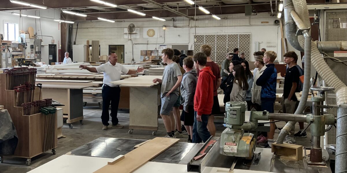 Students on a tour listening to a representative from Calmar Manufacturing.